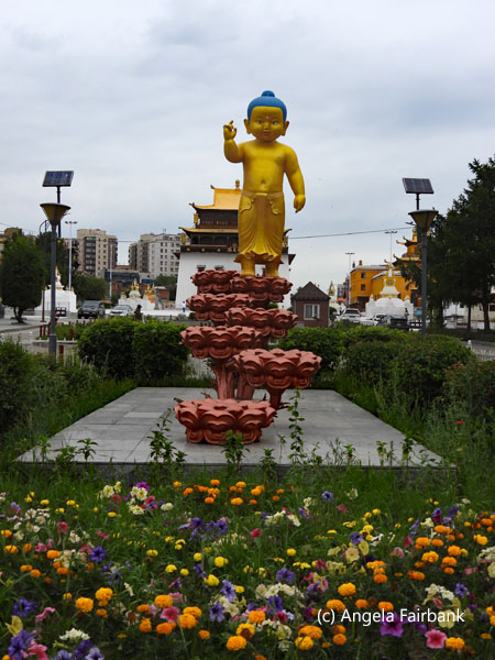 small Buddha in gold behind flowers