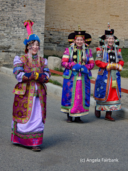 women in costume coming out of monastery gates