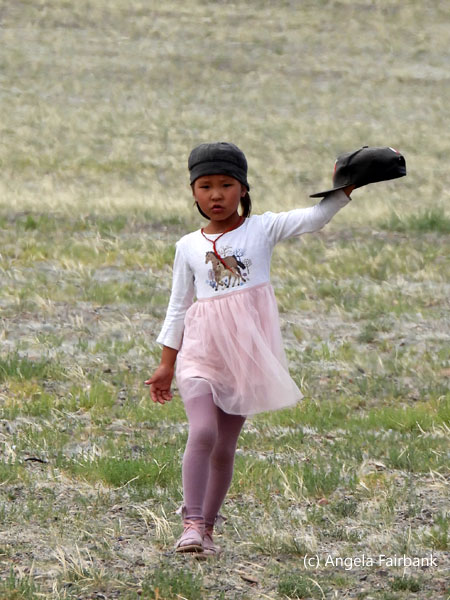 girl in pink skirt holding black hat