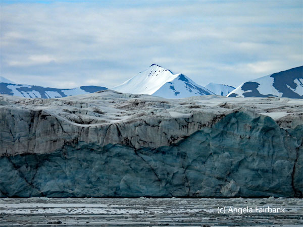 mountain peaking up over dirty glacier edge