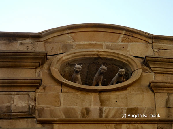 statues of three cats on building in old town
