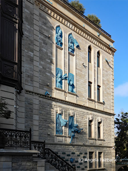 grey stone building wih blue statues at windows