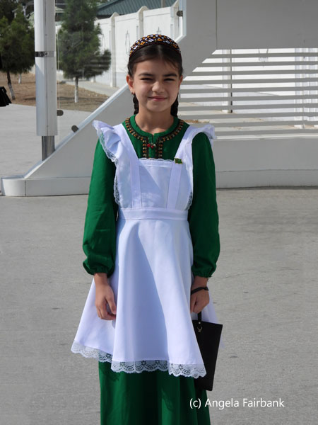 school girl in white pinafore at bus stop