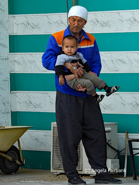 man in white head scarf holding small boy