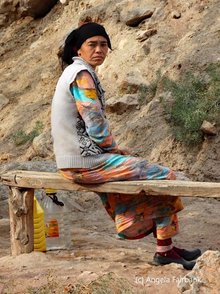 woman in black headscarf and grey sweater witting on a bench