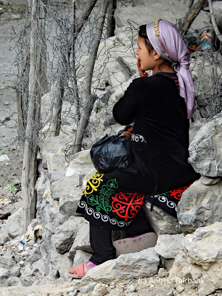 girl in light purple head scarf sitting on rocks