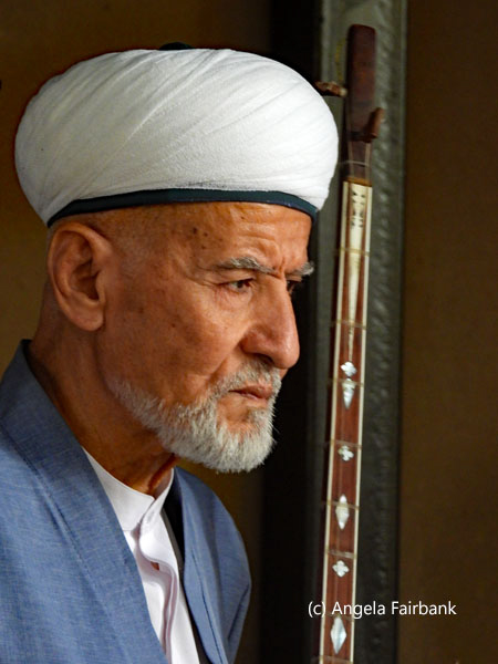musician in white turban with stringed instrument at Paper Mill