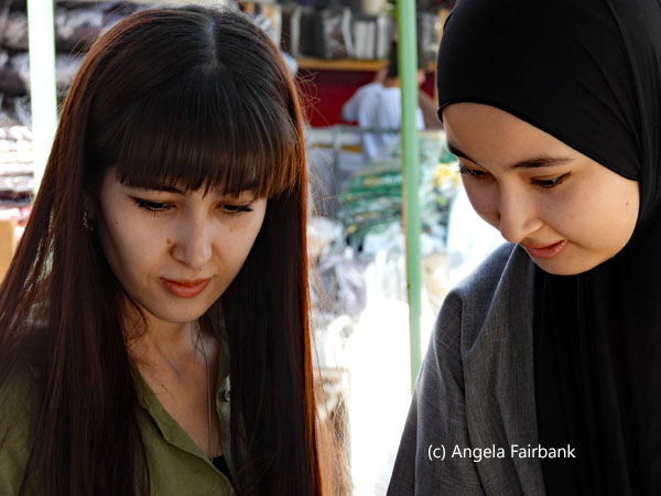 two young women admiring wares in market