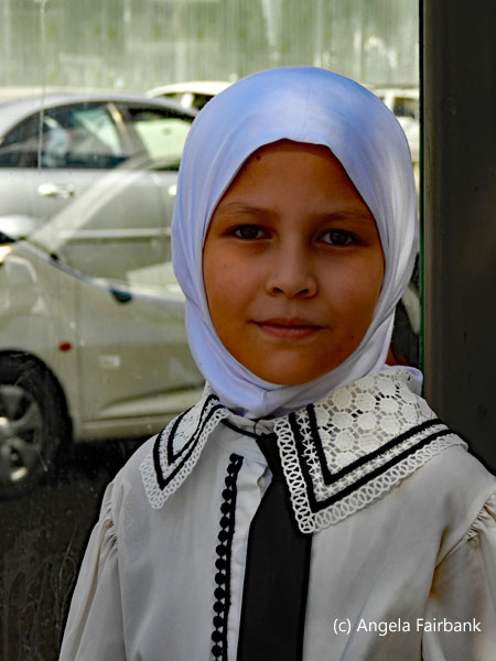 girl in white headscarf at bus stop
