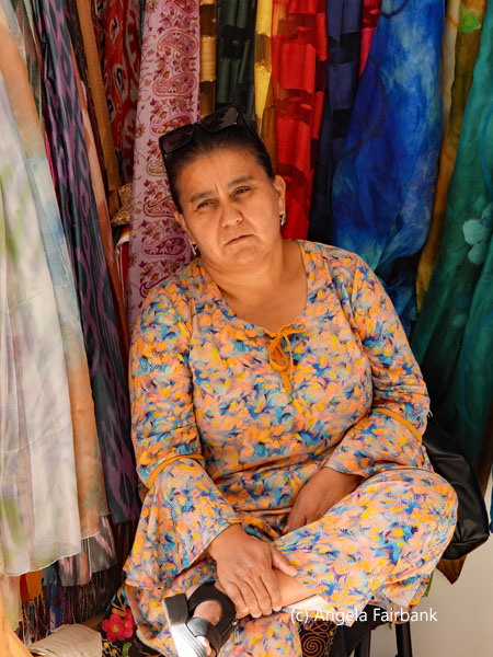 woman sitting with leg crossed selling scarves