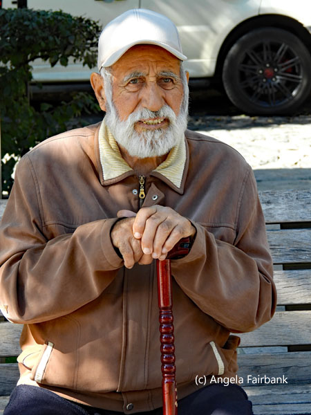 old man with stick and white cap