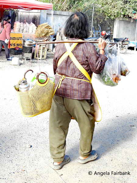 woman carrying bags on pole