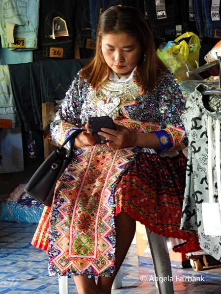 young hmong woman in traditional dress with phone
