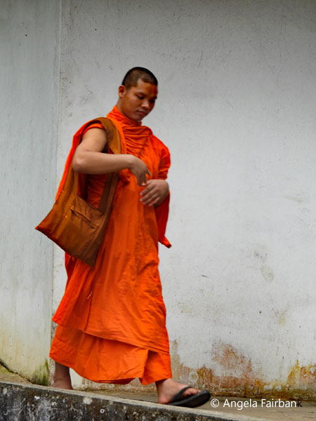 monk walking in front of white wall