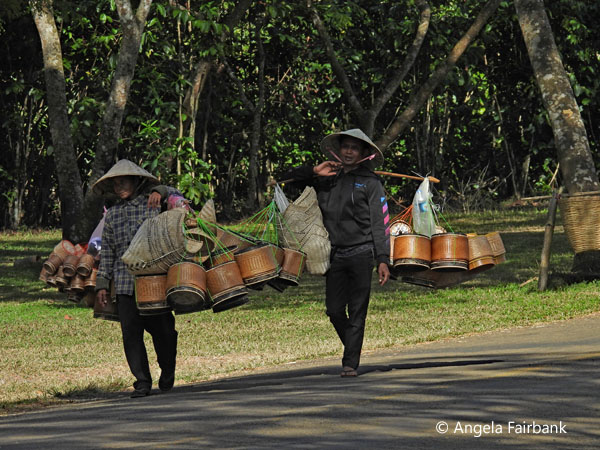 women in conical hats and pots on sticks