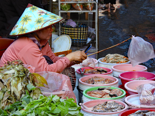 woman in conical hat swishing away flies with plastic bag on stick