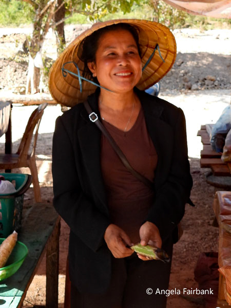 vendor in conical reed hat selling almonds
