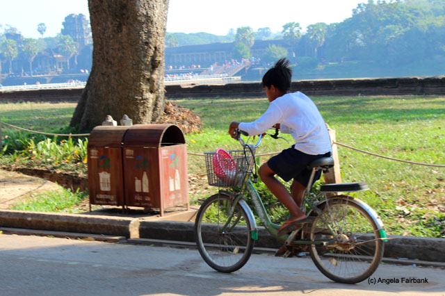 Bicyclist rides past Angkor Wat