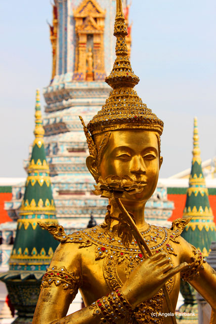 gold statue at Wat Phra Kaeo temple complex with buildings in background