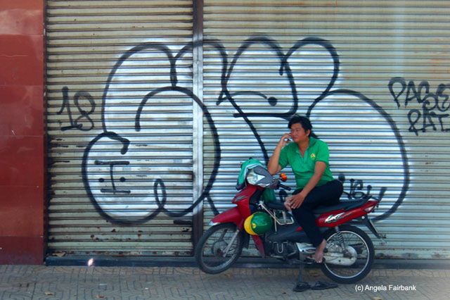 Grab employee on phone resting on scooter