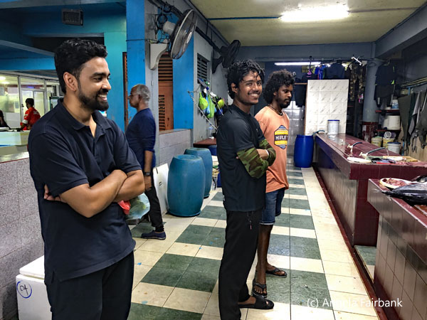 youth watching men fileting fish
