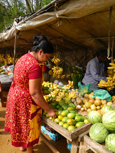 woamn in red at fruit and vegetable stand