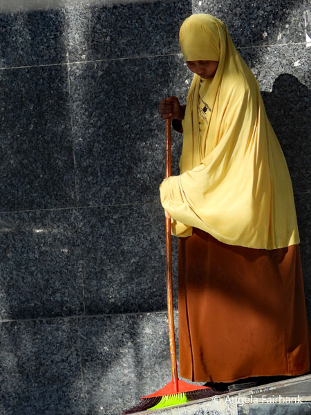 woman sweeping steps of hotel