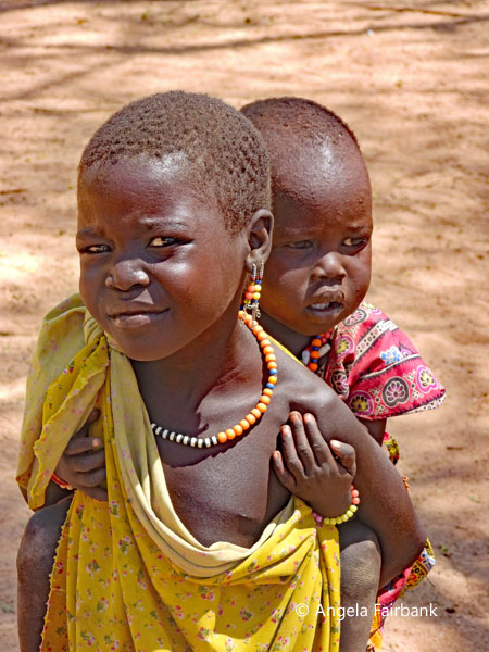 child in yellow carrying sibling on back 
