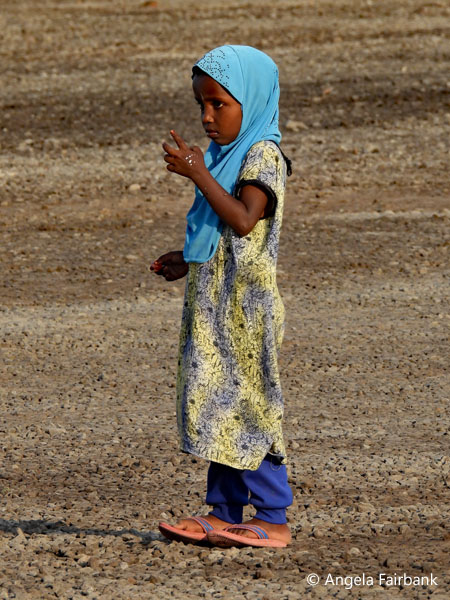 girl on blue veil outside mosque
