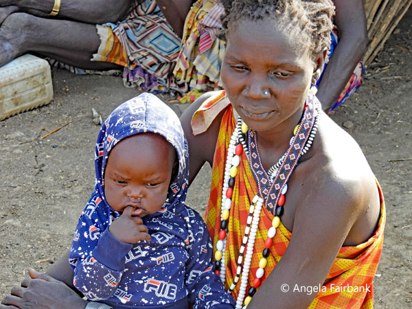 Toposa woman sitting with warmly clad child