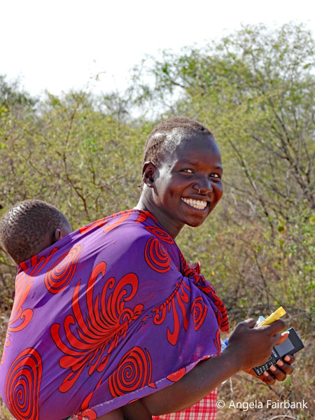 smiling Toposa woman carrying her child on her back