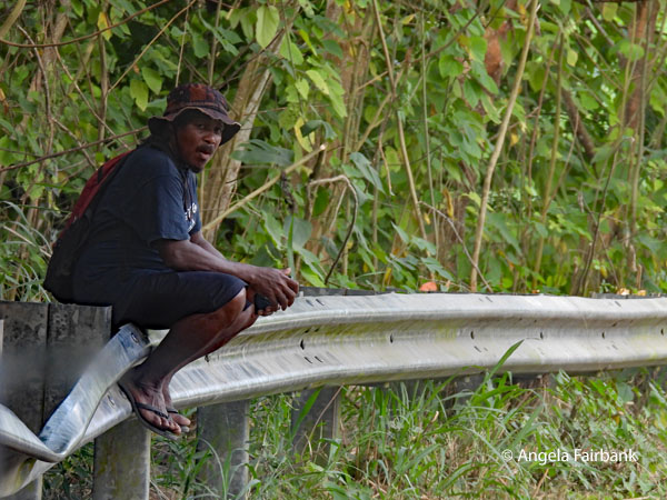 man sitting on road railing