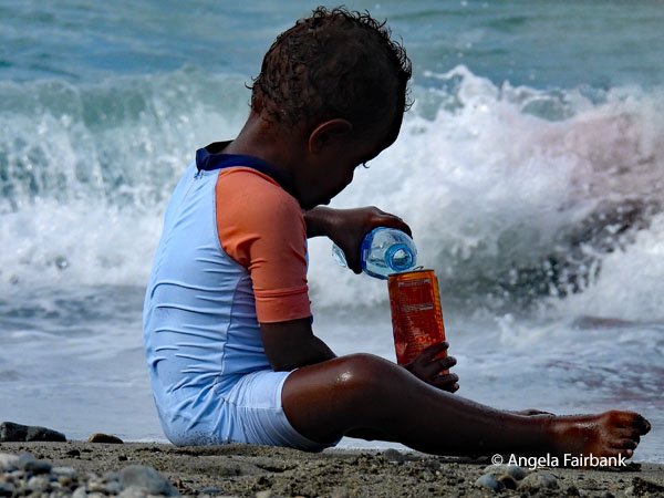 boy pouring water into orange can