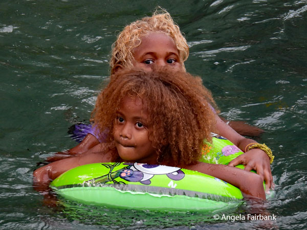 two girls in water with green float 1
