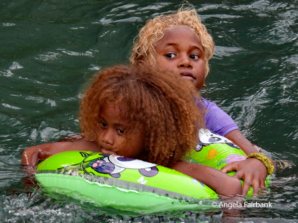 two girls in water with green float 2