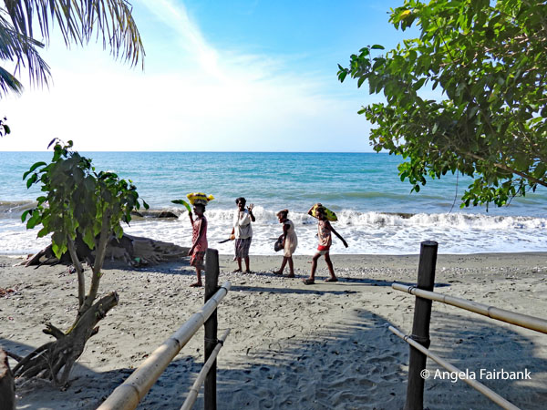 women and chldren walking along beach at cacao farm
