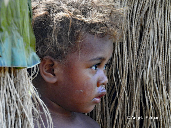 child between grass skirts