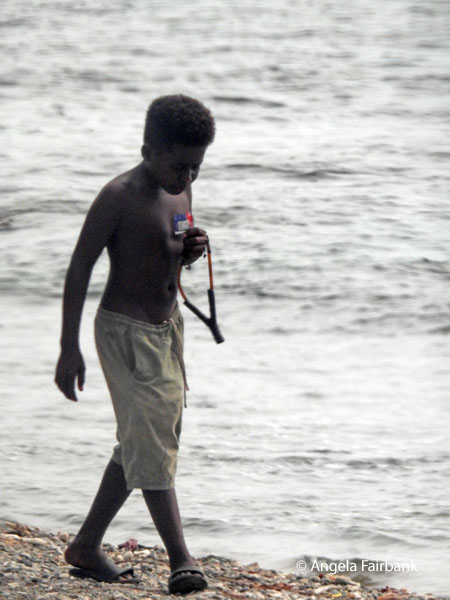 boy on beach with slingshot