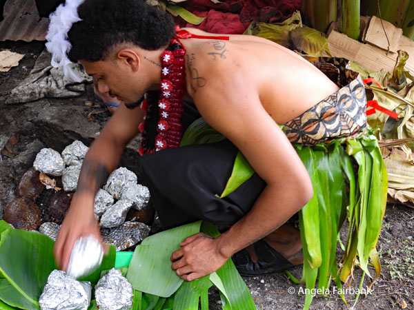 male dancer pulling our food from the underground oven