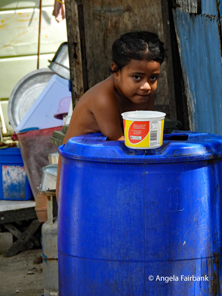 girl washing in large bucket of water
