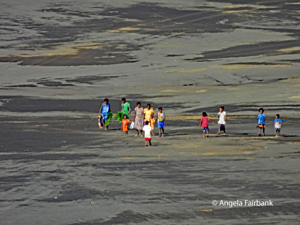 locals walking on volcanic sand