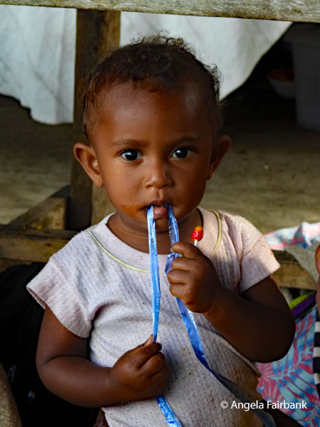 boy at market with blue ribbon in mouth