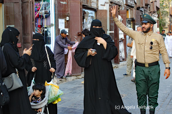 street scene with three women in black and one policeman in al balad