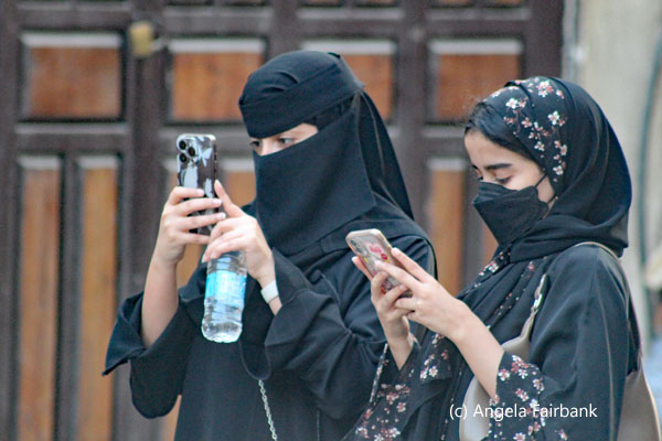 two womanin black checking their phones