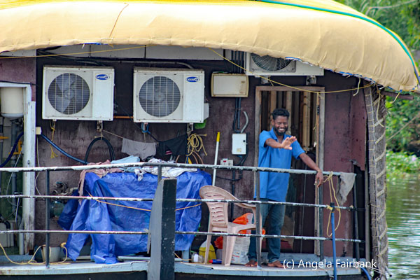 man in blue waving from houseboat