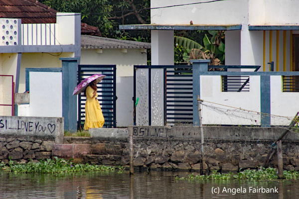 woman in yellow on phone walking by houses