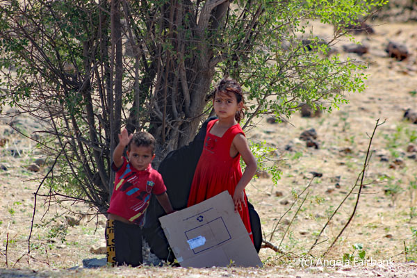 children waving from road side
